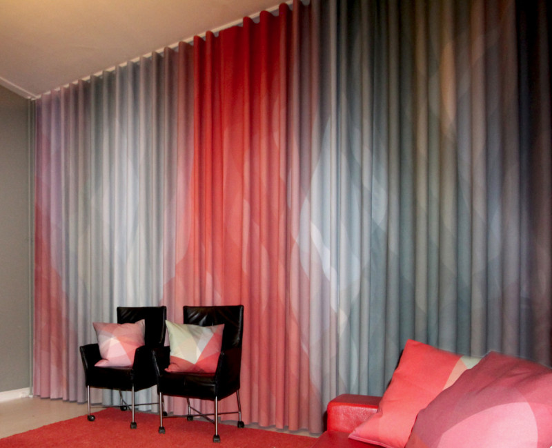 Gordijn en kussens in roodtinten en grijsblauw, afgestemd op het interieur